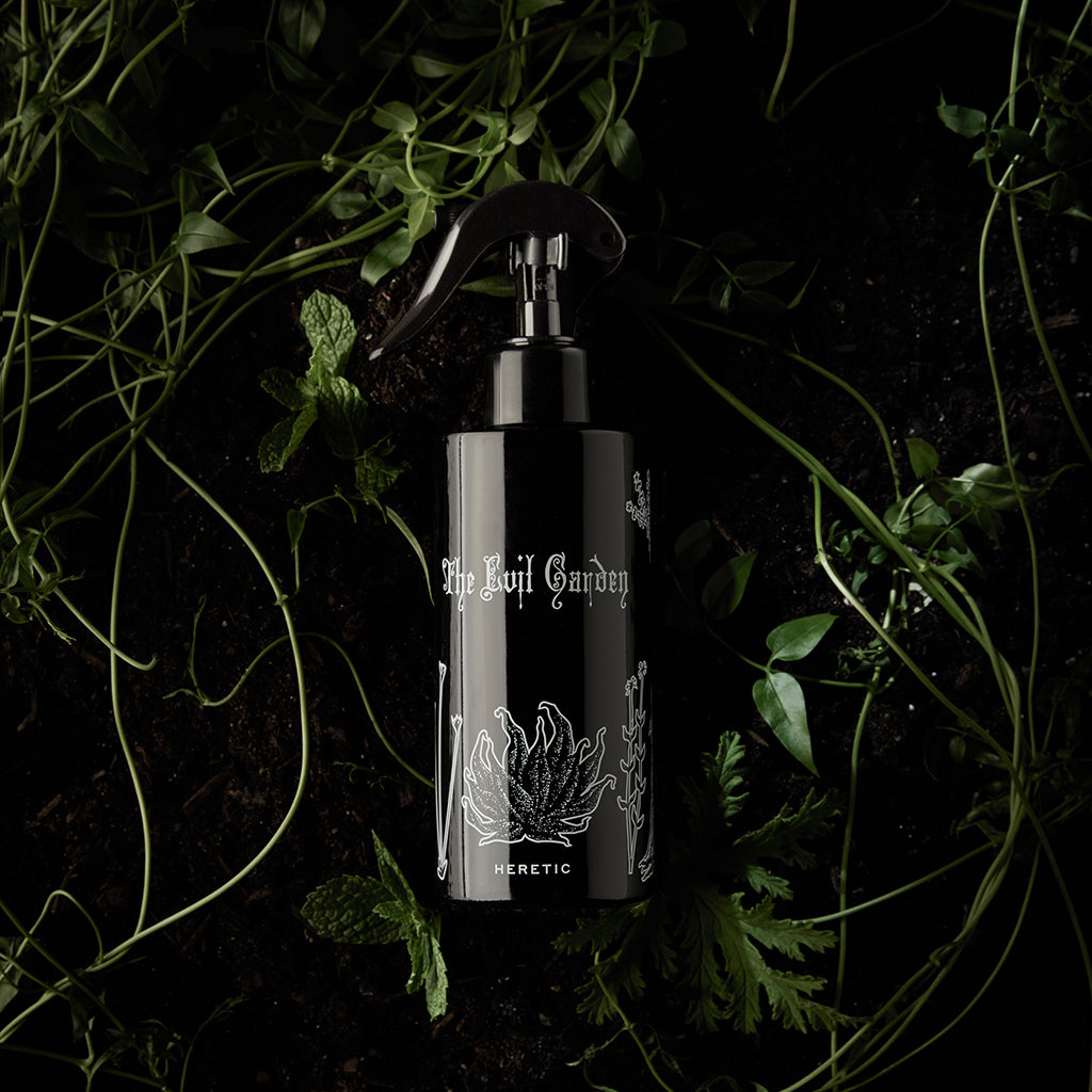 Black spray bottle with 'The Evil Garden' branding on a dark background with greenery