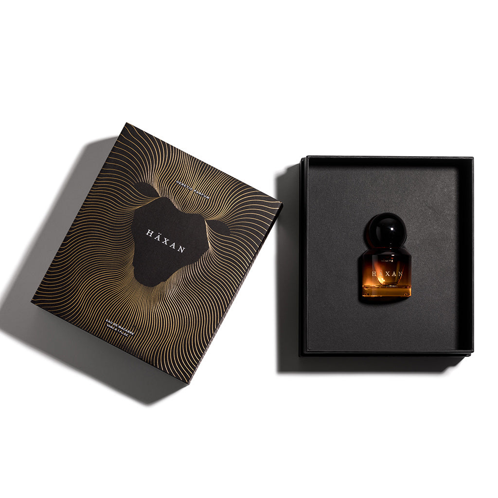 Perfume bottle in a black box with 'Häxan' packaging on a white background