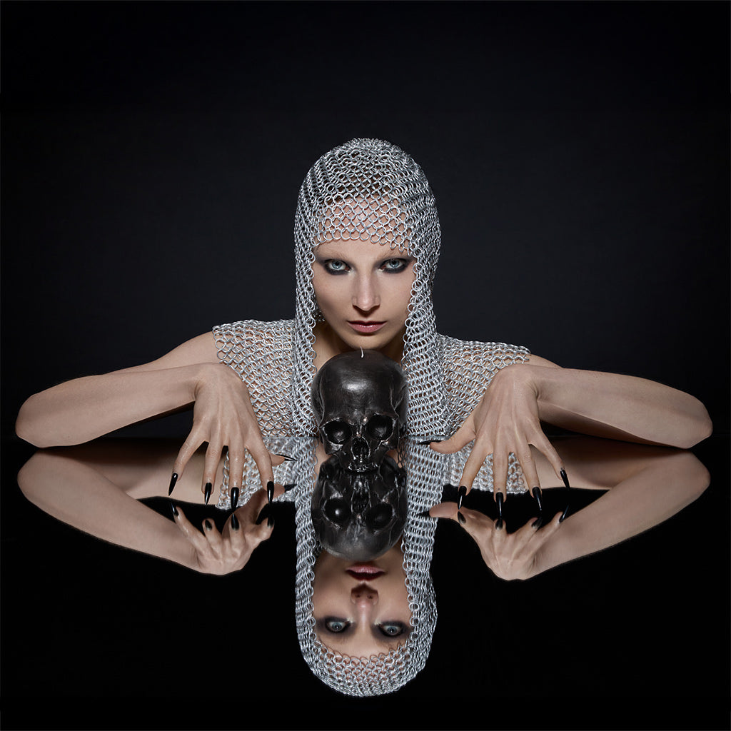 Person wearing a chainmail headpiece with a skull in front of a black background