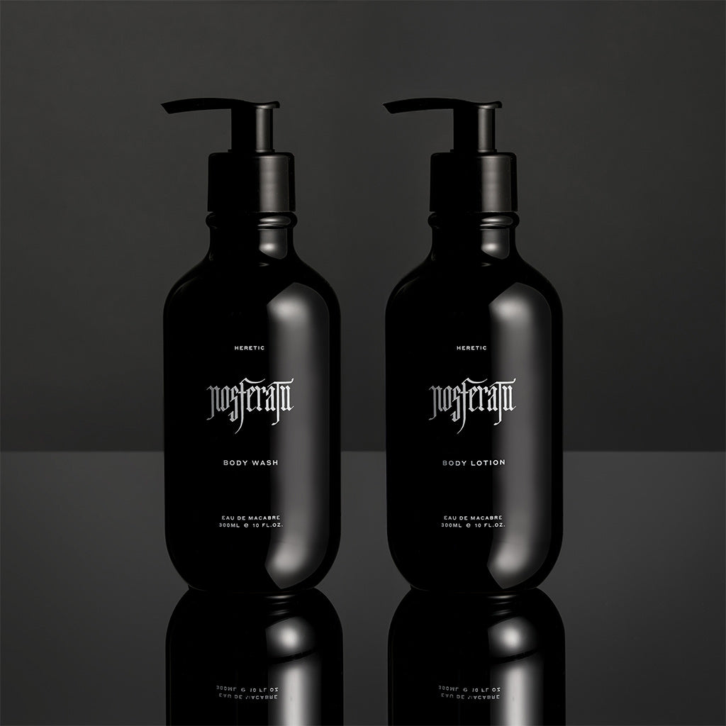 Two black bottles of Heretic Nosferatu body wash and lotion on a reflective surface with a dark background.