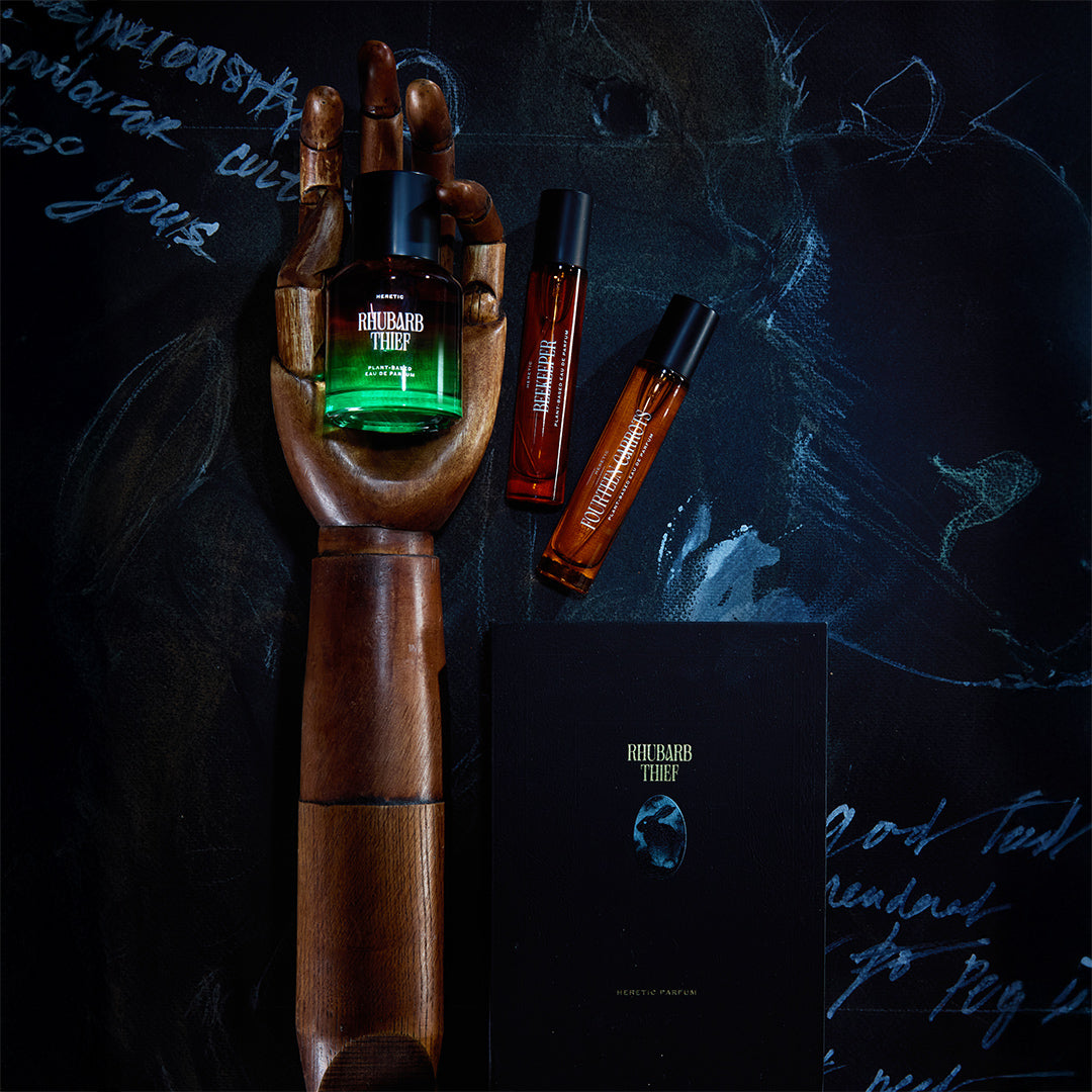 Wooden hand holding a bottle of Richard Tufel perfume with other bottles and packaging on a dark background.