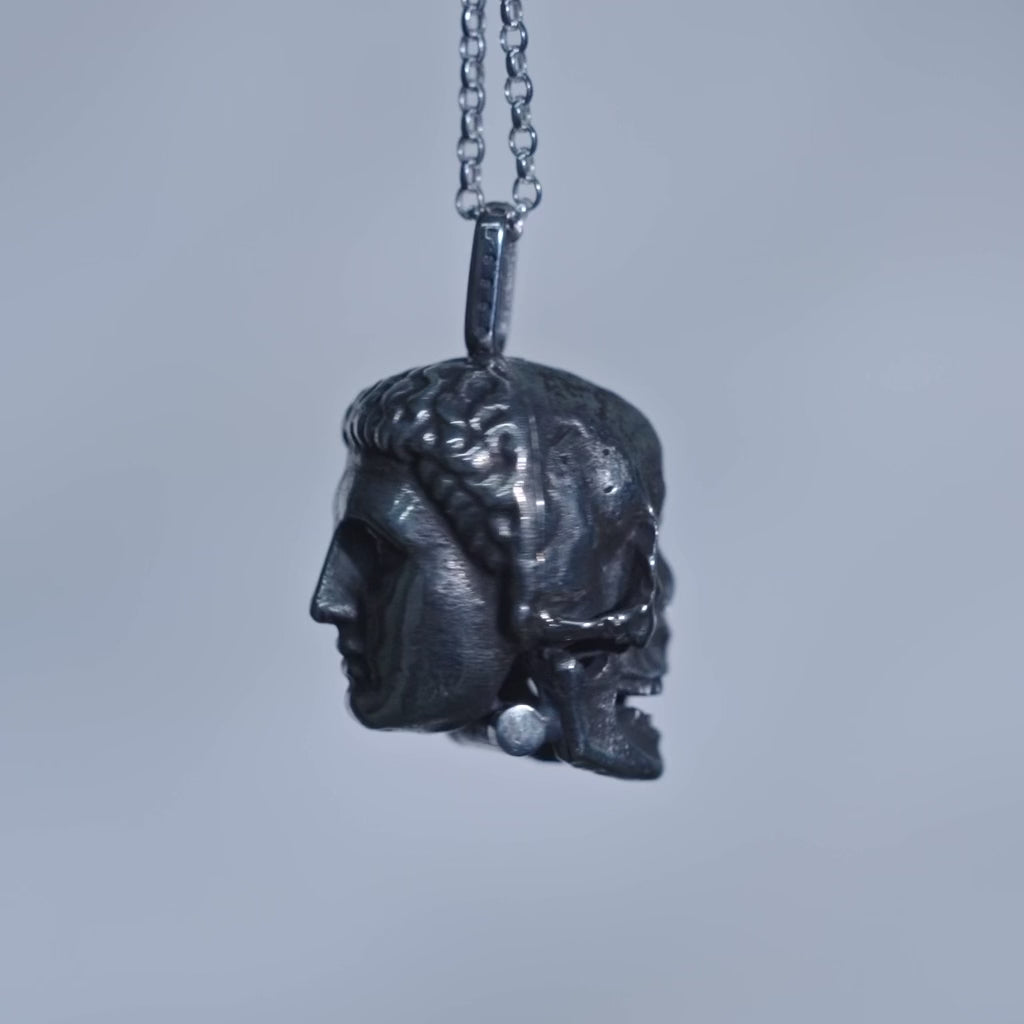 video of necklace spinning around so you can see one side of the pendant is a human face, the other side is a skull.